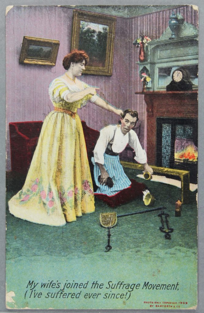 an ant suffragette postcard showing a woman holding a mans ear as he does the housework
