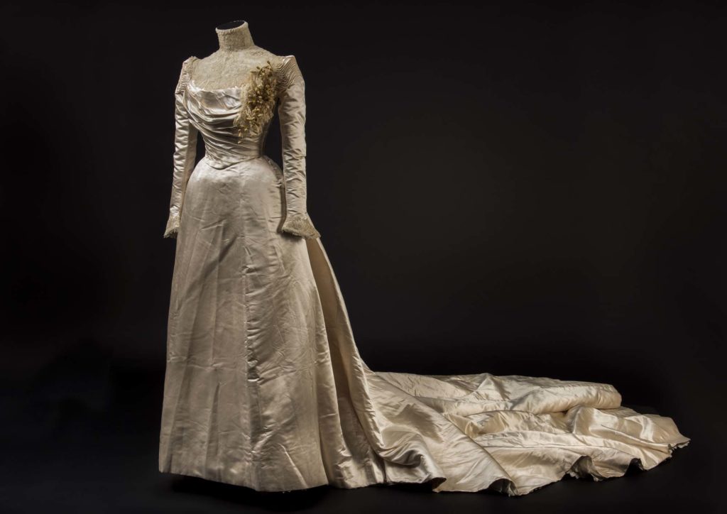 a photo of a wedding dress in silk with long sleeves and a very long trane